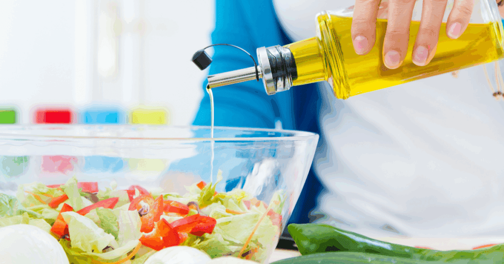 Bottle of vegetable oil placed beside fresh vegetables in a kitchen setting